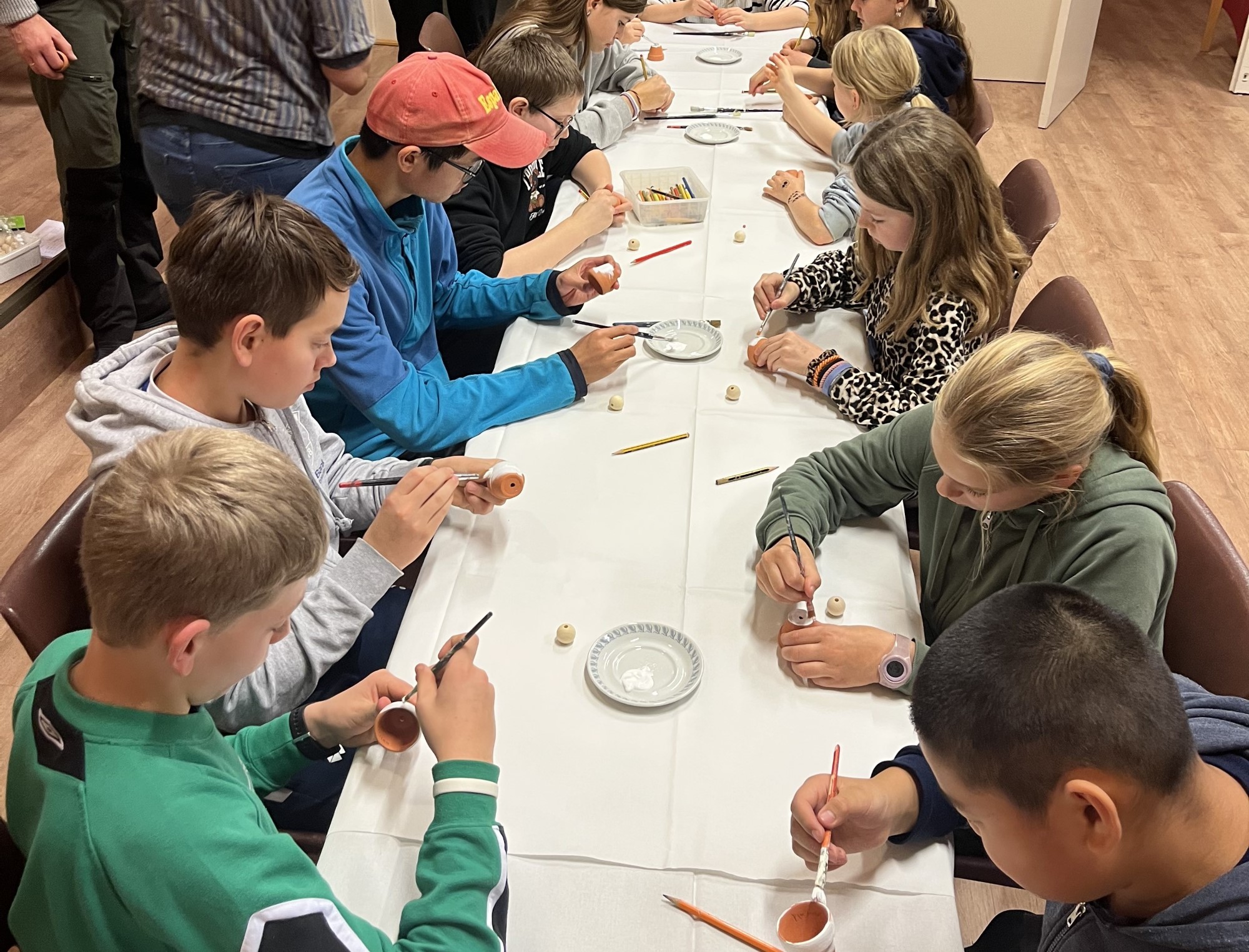 Bildet viser mange barn som sitter rundt et bord og lager julepynt
