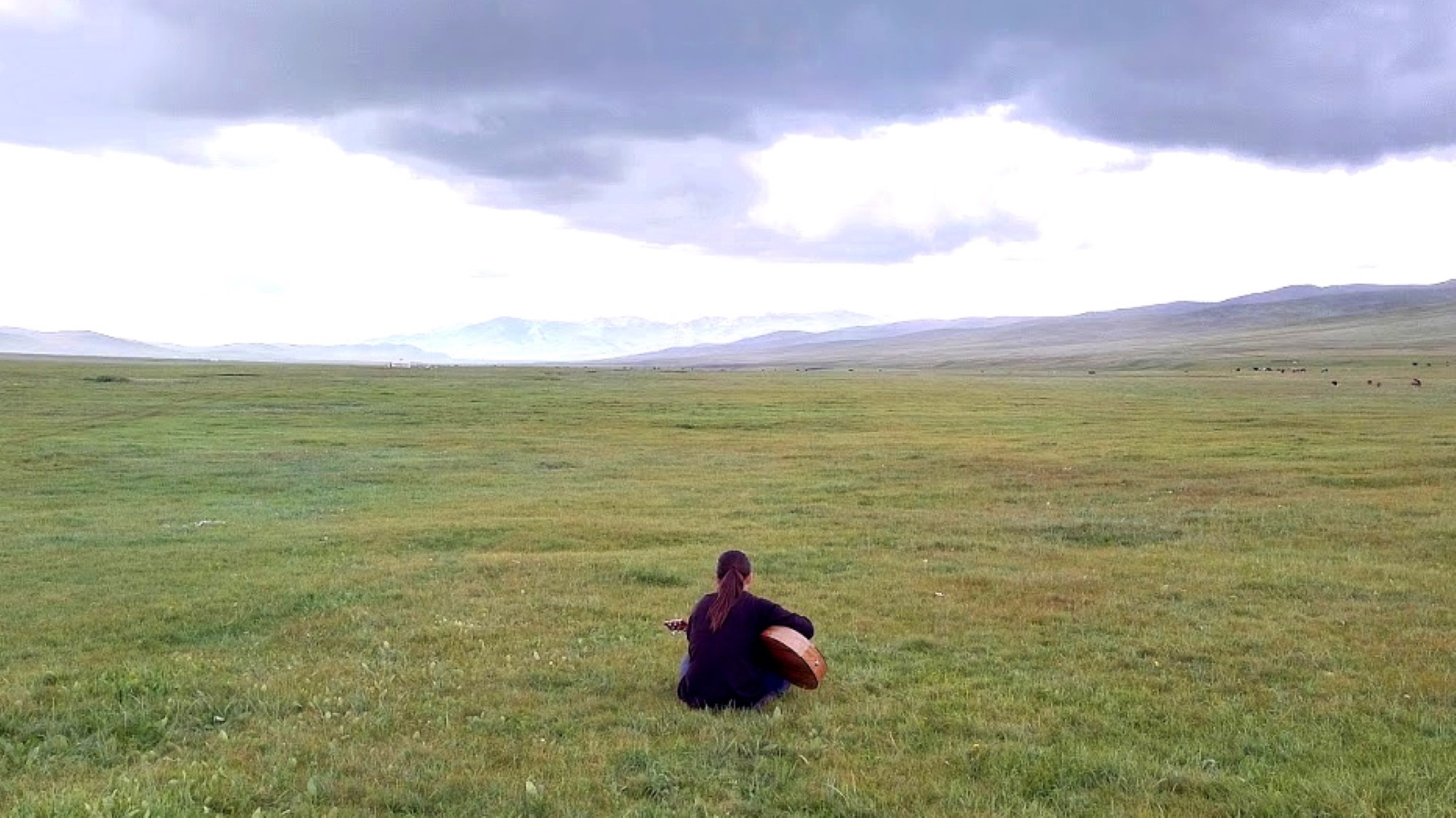 Kvinne spiller gitar og lovsynger på mongolsk steppe