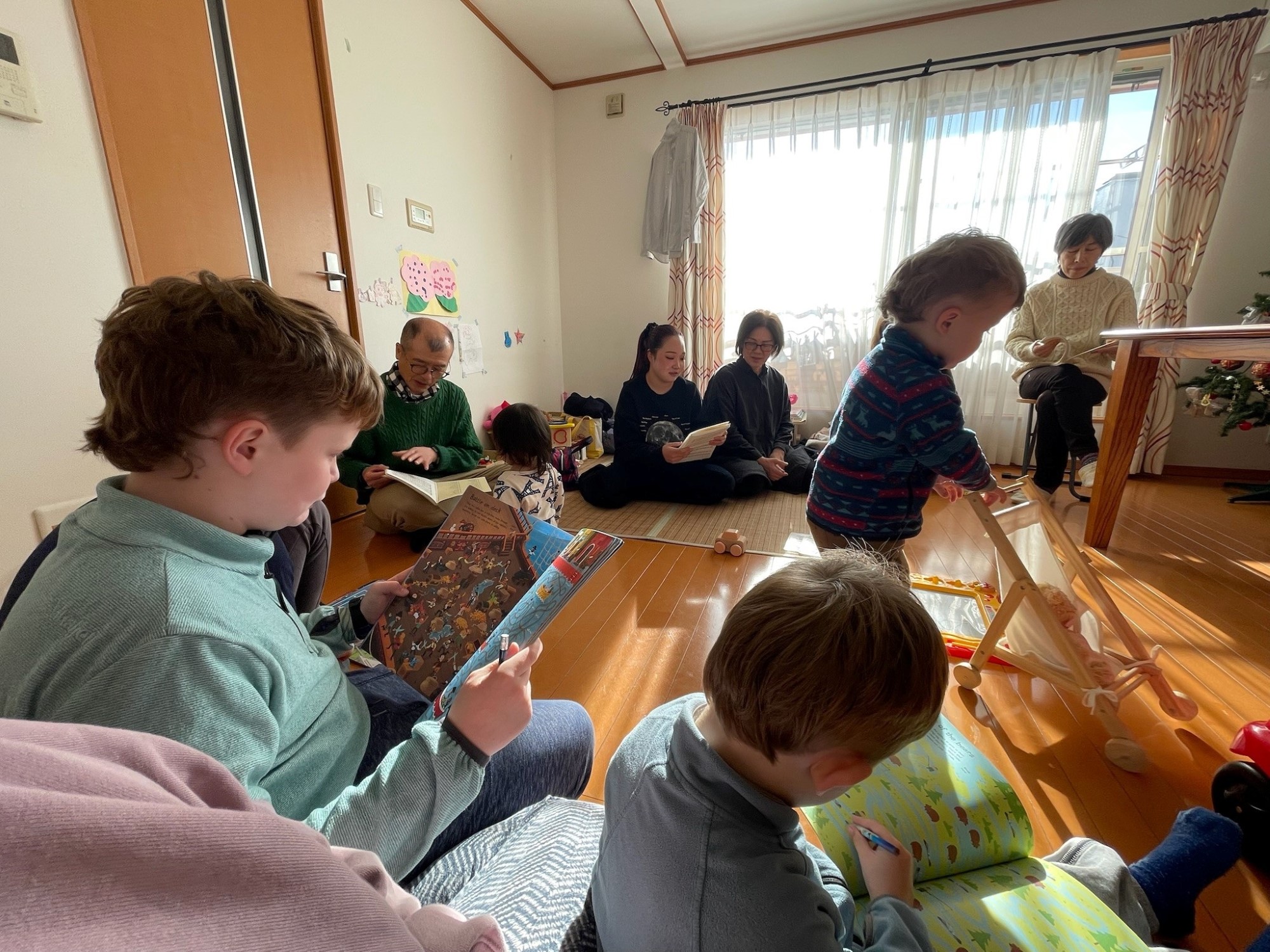 Barn og voksne sitter på golvet på familiemøte. Barna leker.