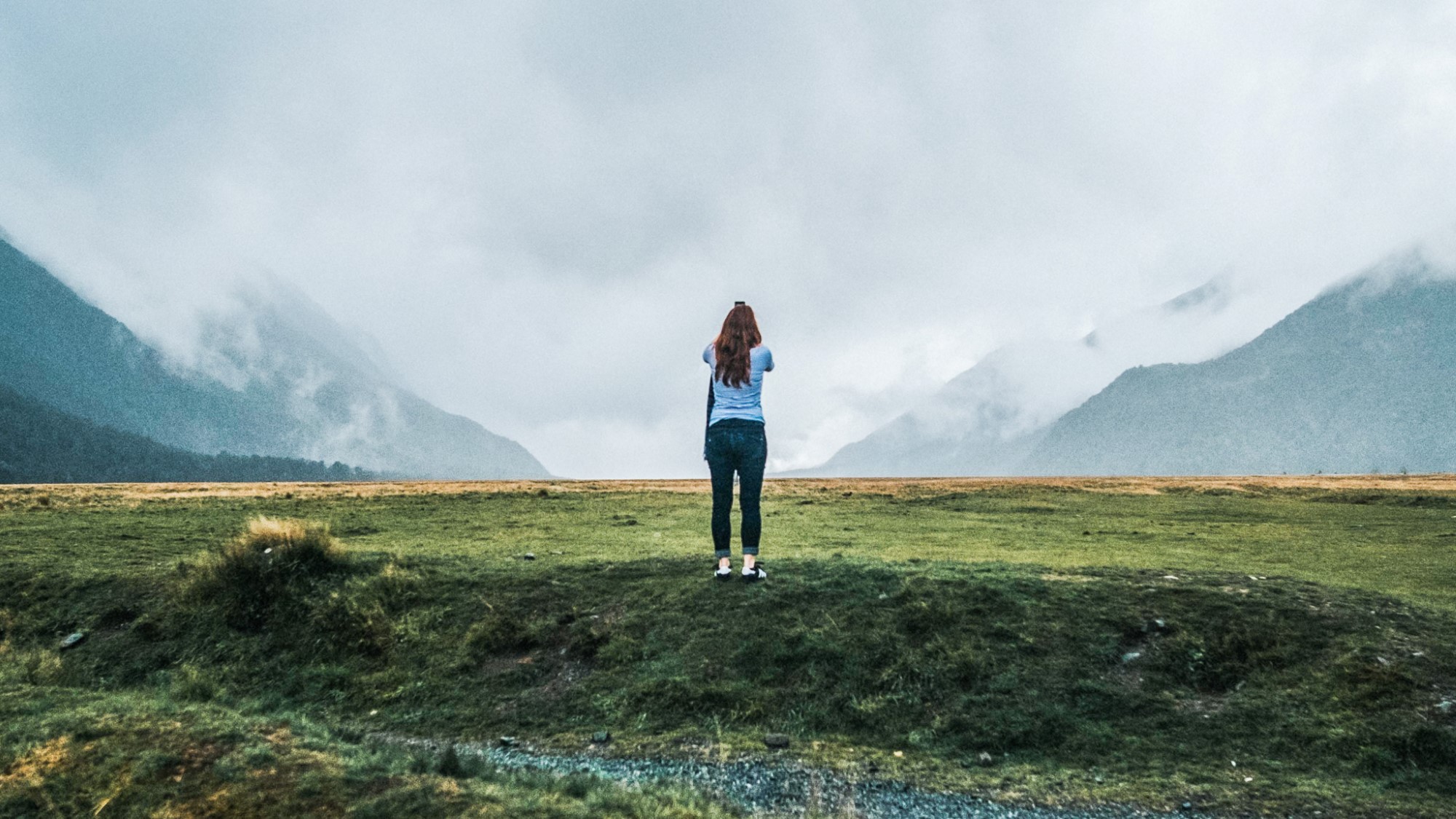 Kvinne ser utover landskap med skyfull himmel