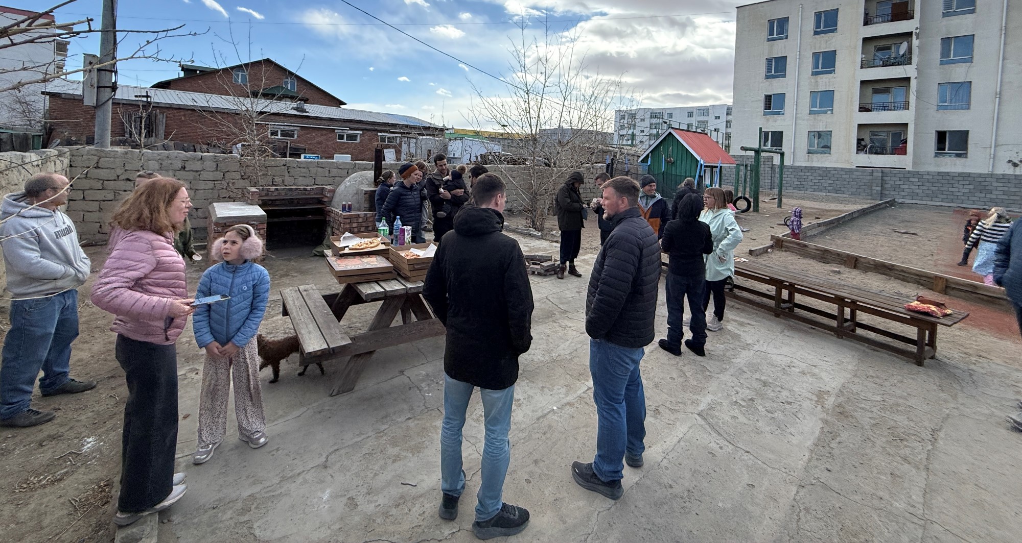 Sosial samling med pizza og samvær. Alle står ute i hagen.