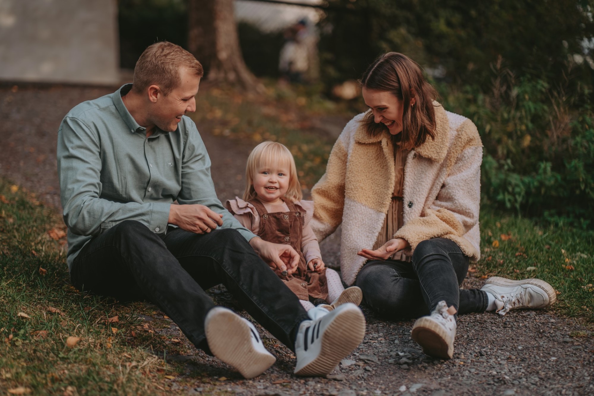 Bildet viser en smilende familie med mor, far og en jente.