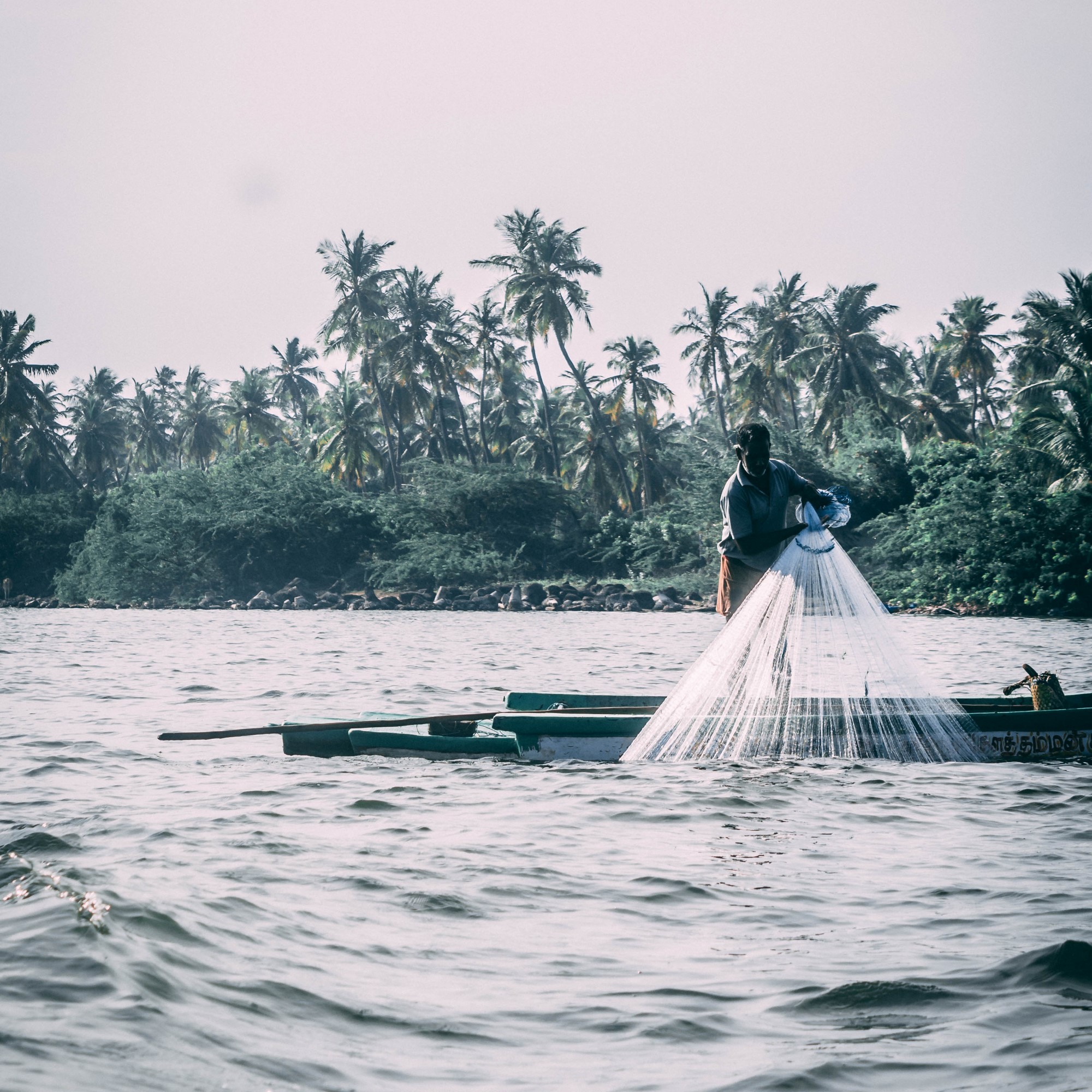 Bilde fra forsiden av Prosjektkatalogen 2024, indonesisk fisker i liten båt kaster garn