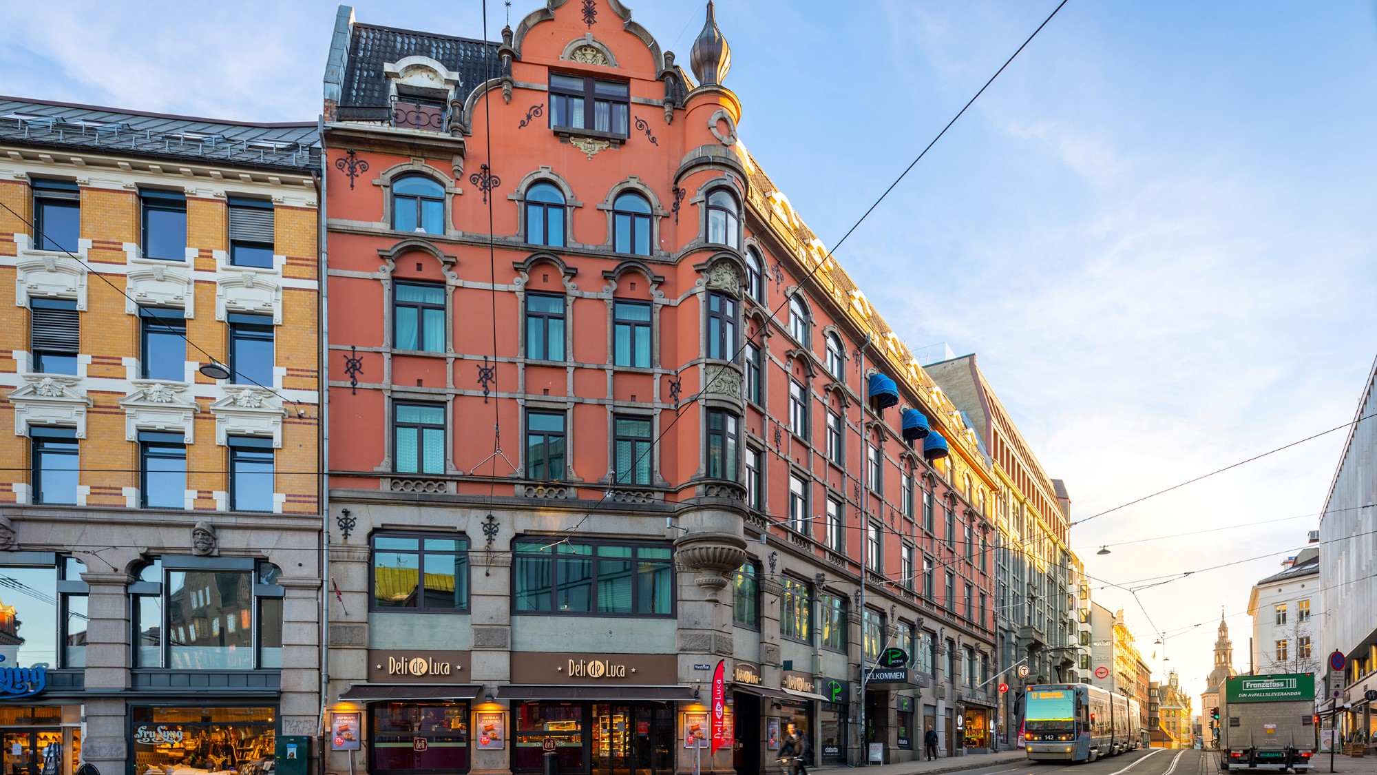 Grensen 19, stor rustrød hjørnebygård med grå ornamenteringer og detaljer, i Grensen i Oslo sentrum