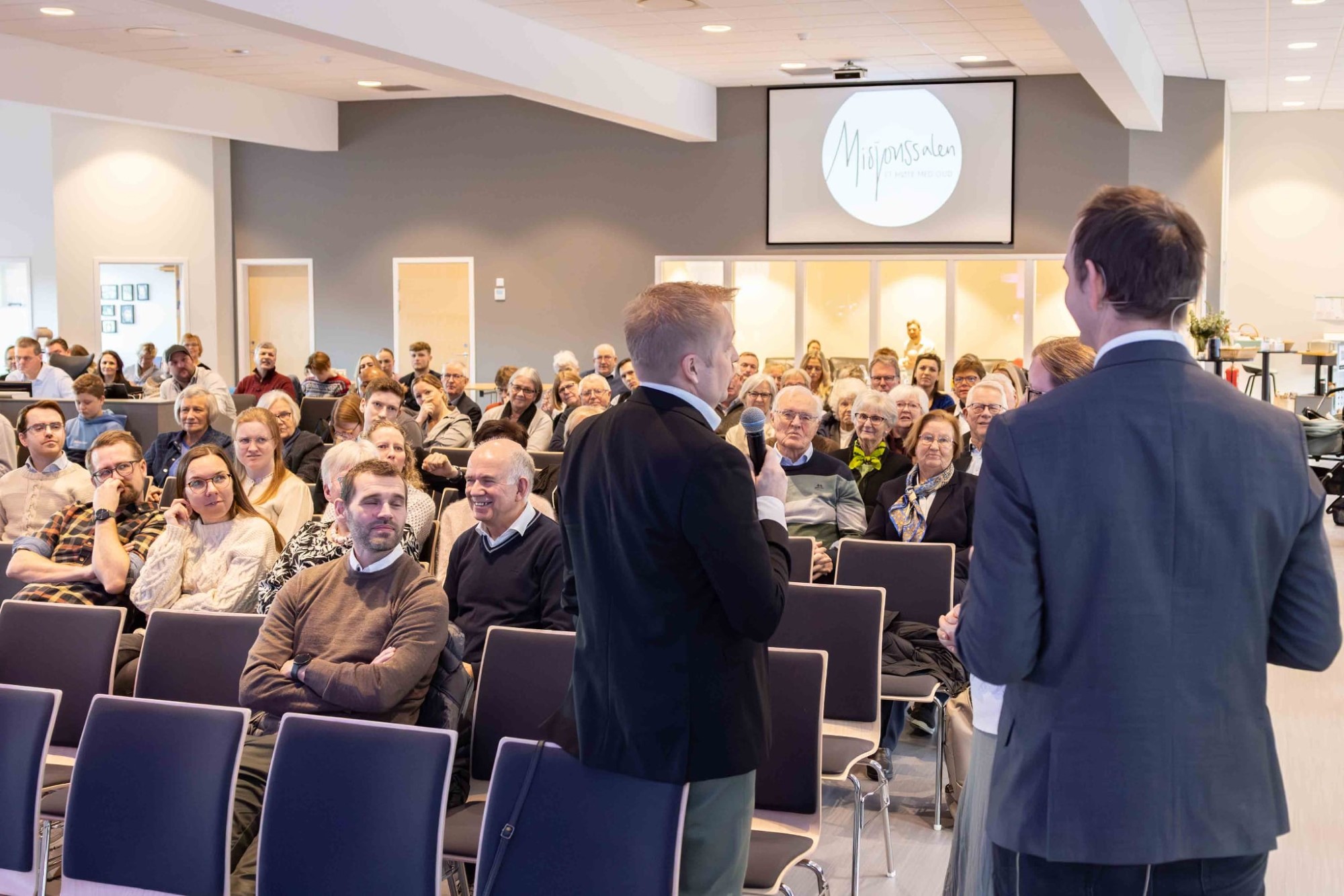 Bildet viser en mann som snakker foren en forsamling