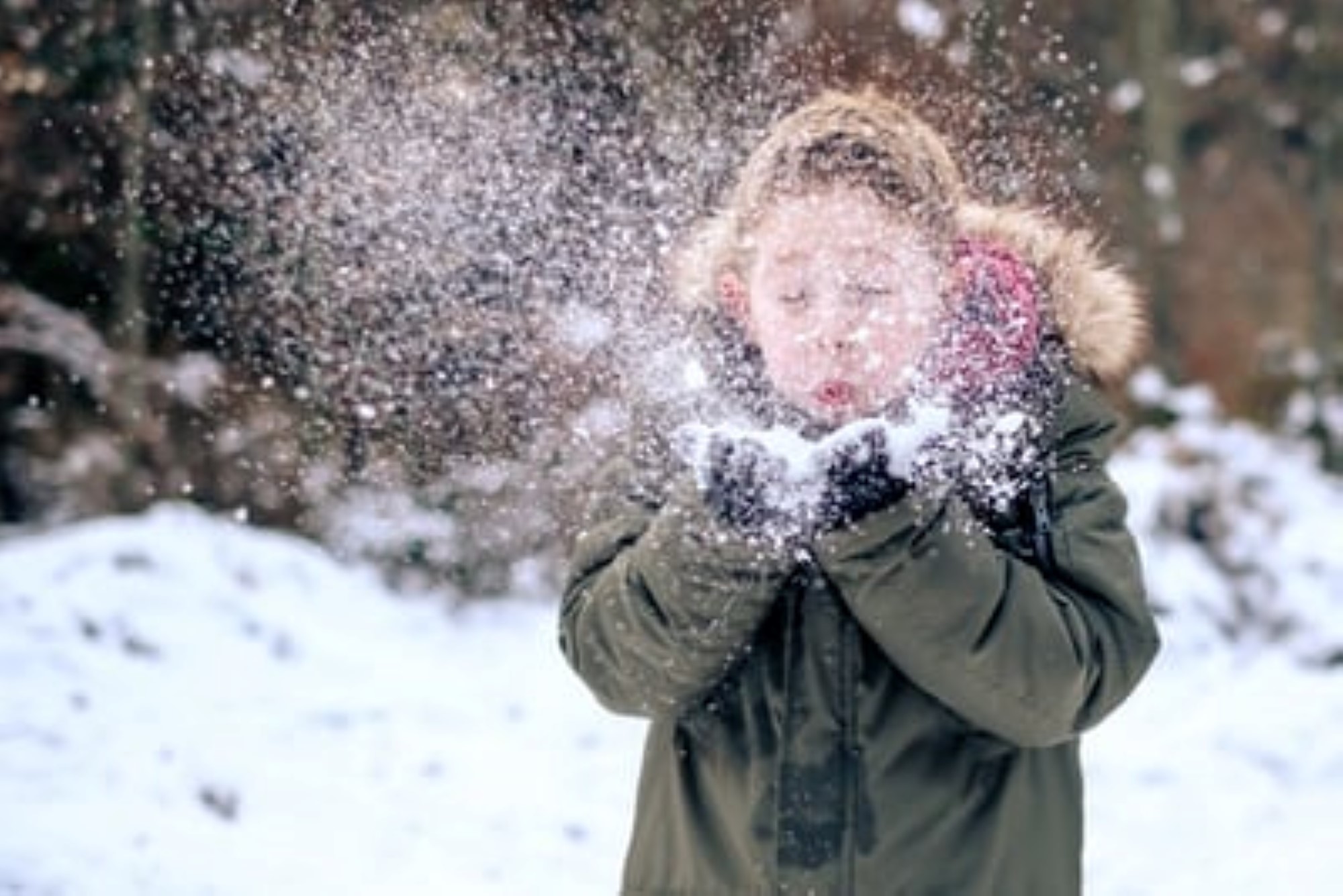 Gutt som blåser bort snø fra hendene