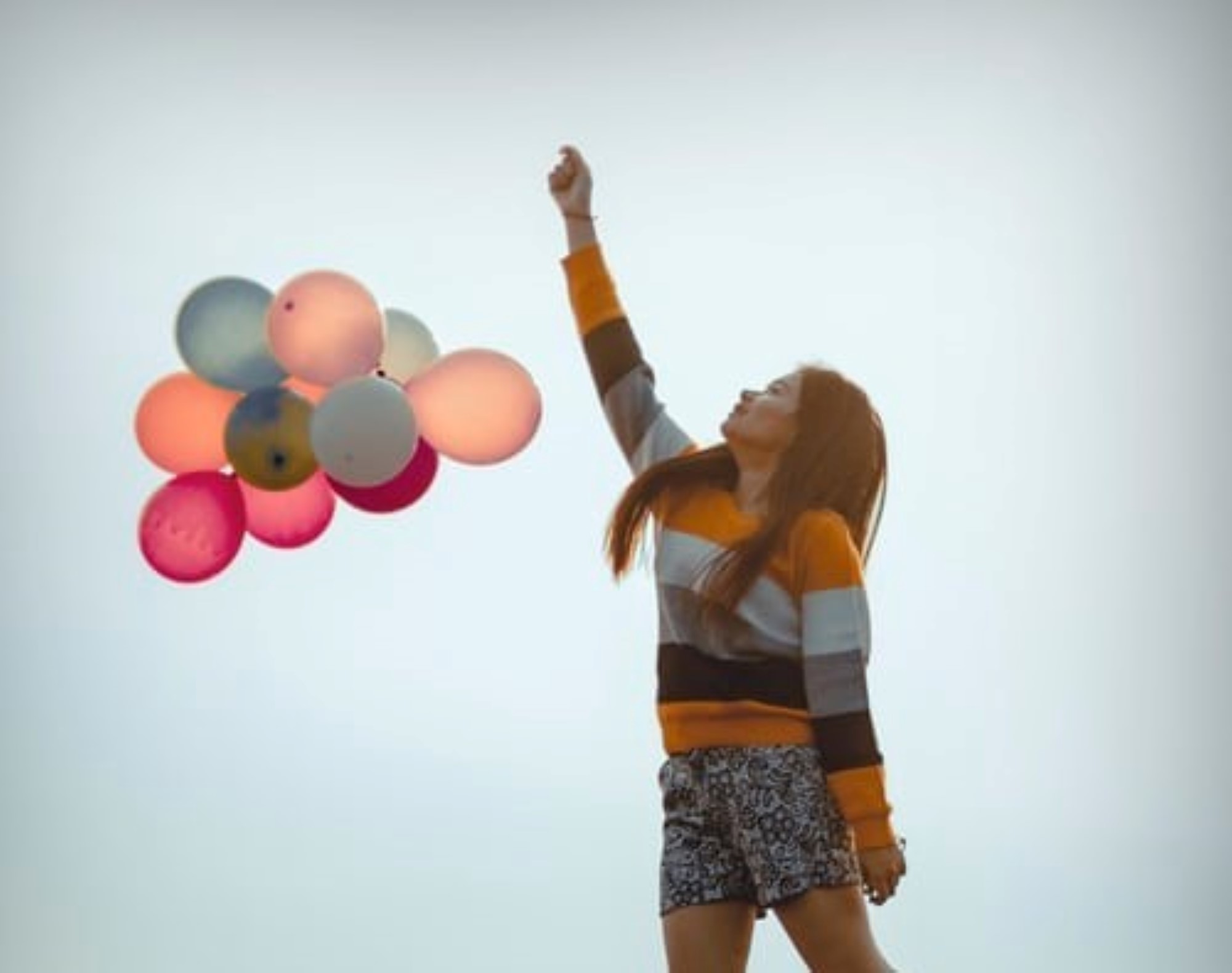 Jente som står med flere ballonger i hånden