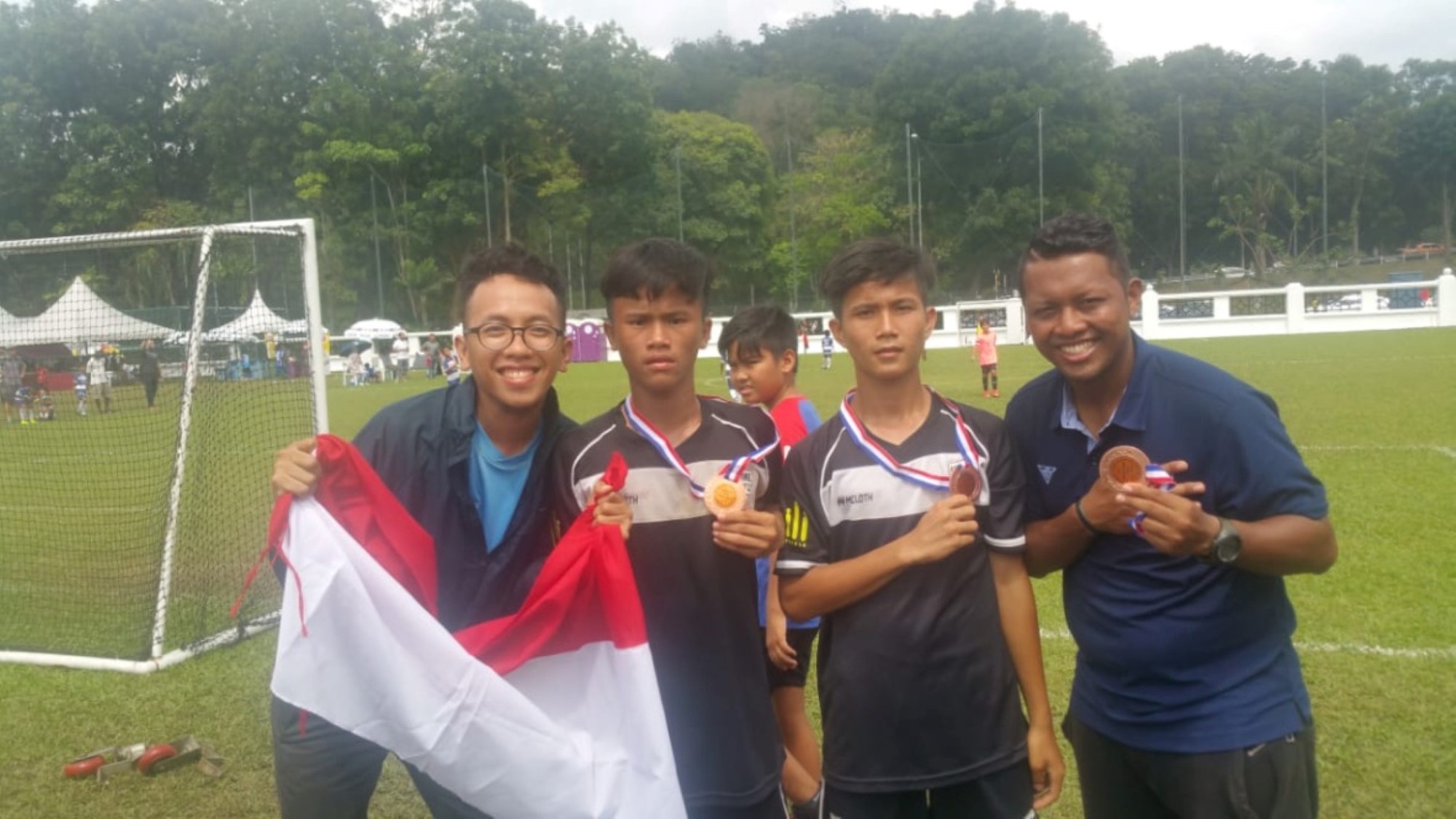 Guttene viser frem medaljer på fotballbanen