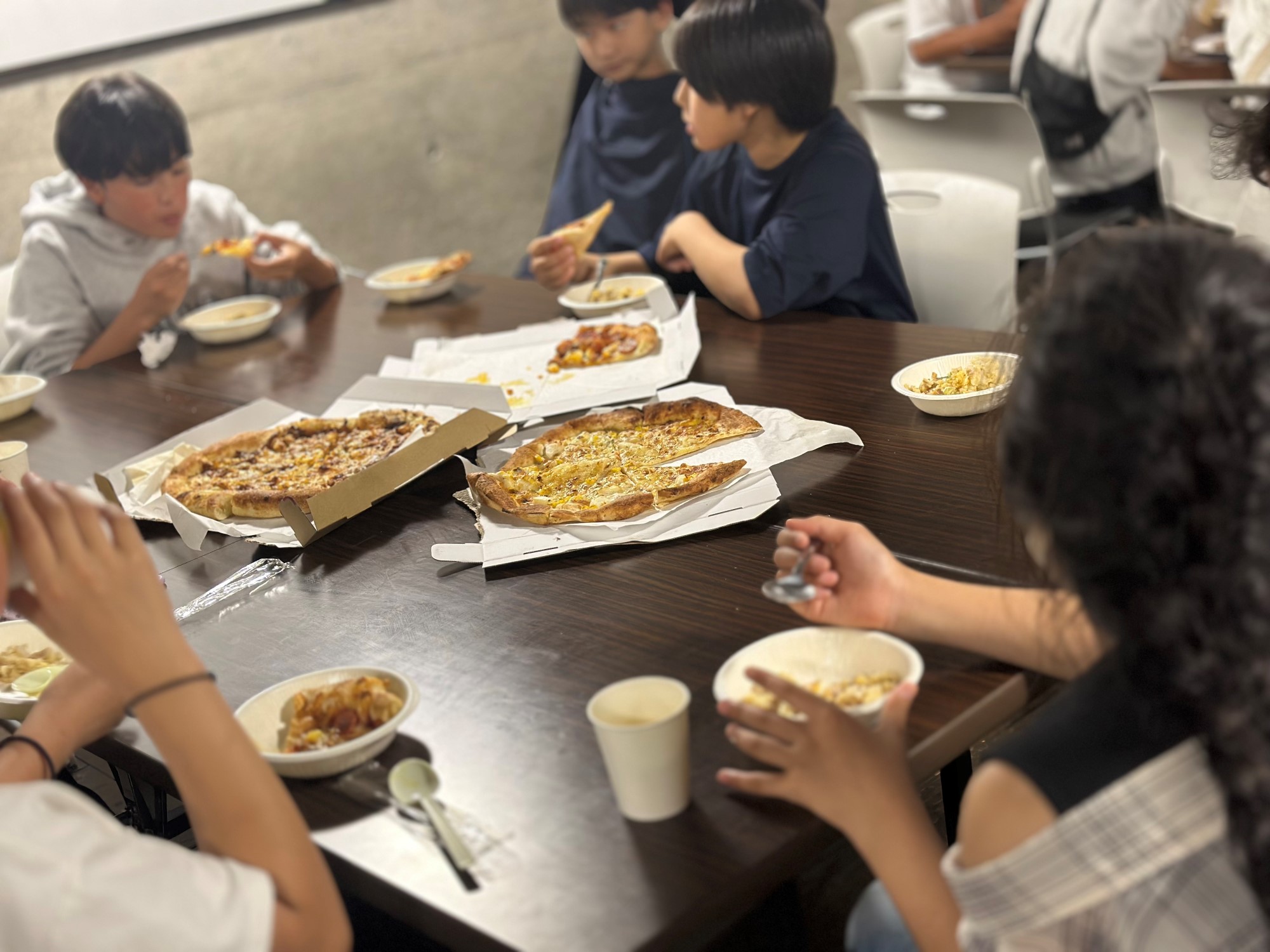 Ungdommer som sitter rundt et bord og spiser pizza
