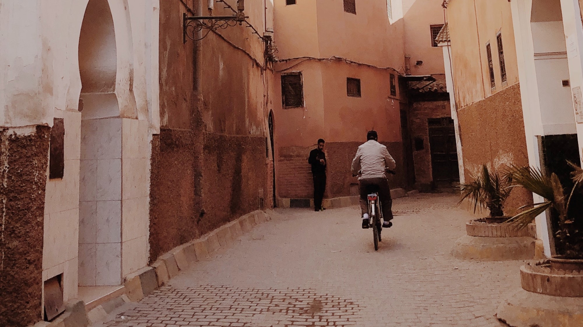 Mann sykler blant gamle murbygninger