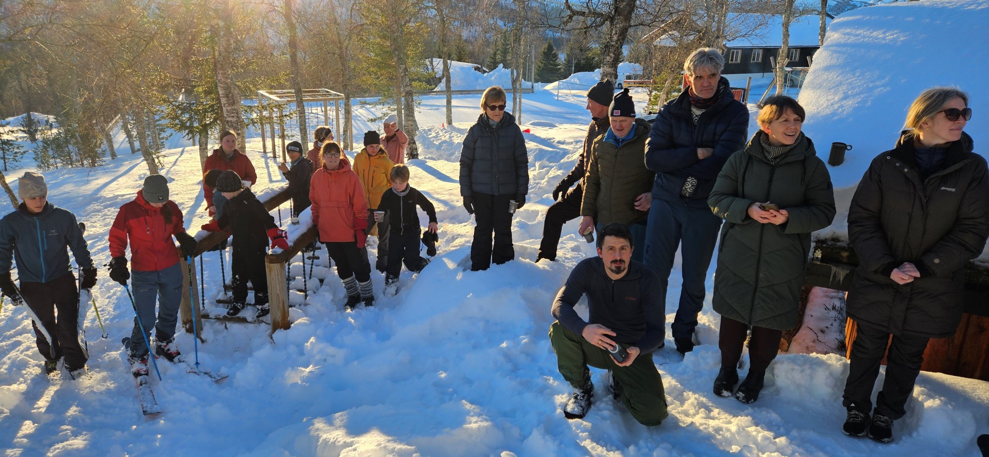 En gruppe glade mennesker foran gapahuk i vintersol