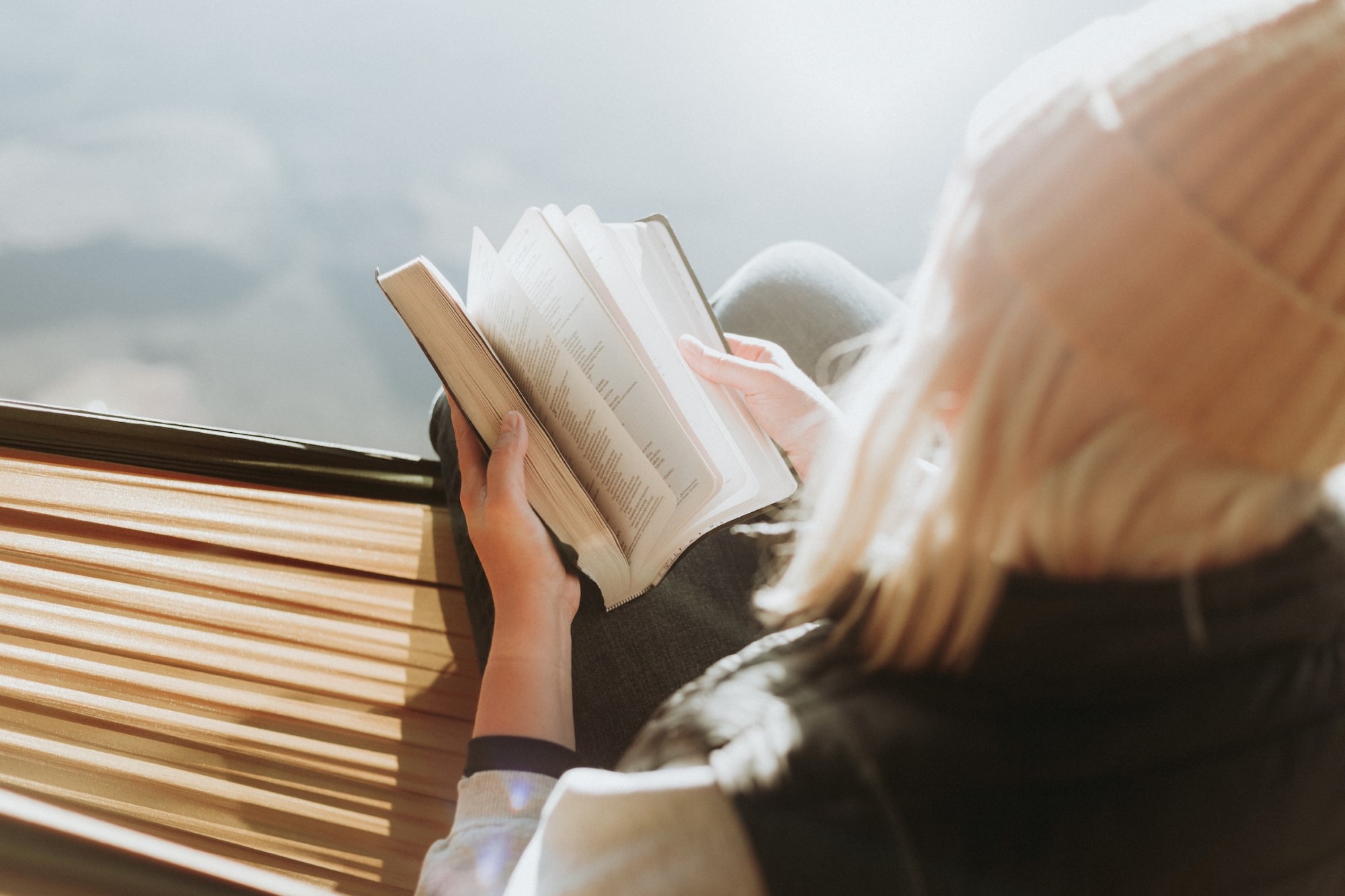 Kvinne som sitter ute og blar i en bibel