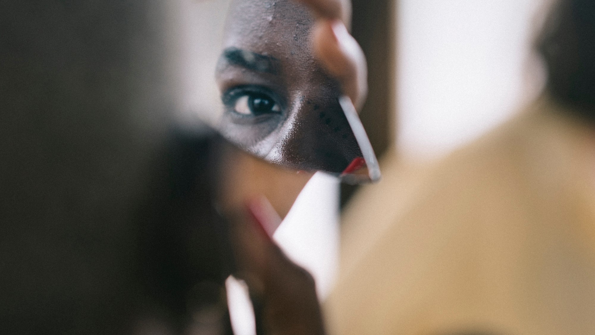 Afrikansk kvinne ser seg i skår av speil