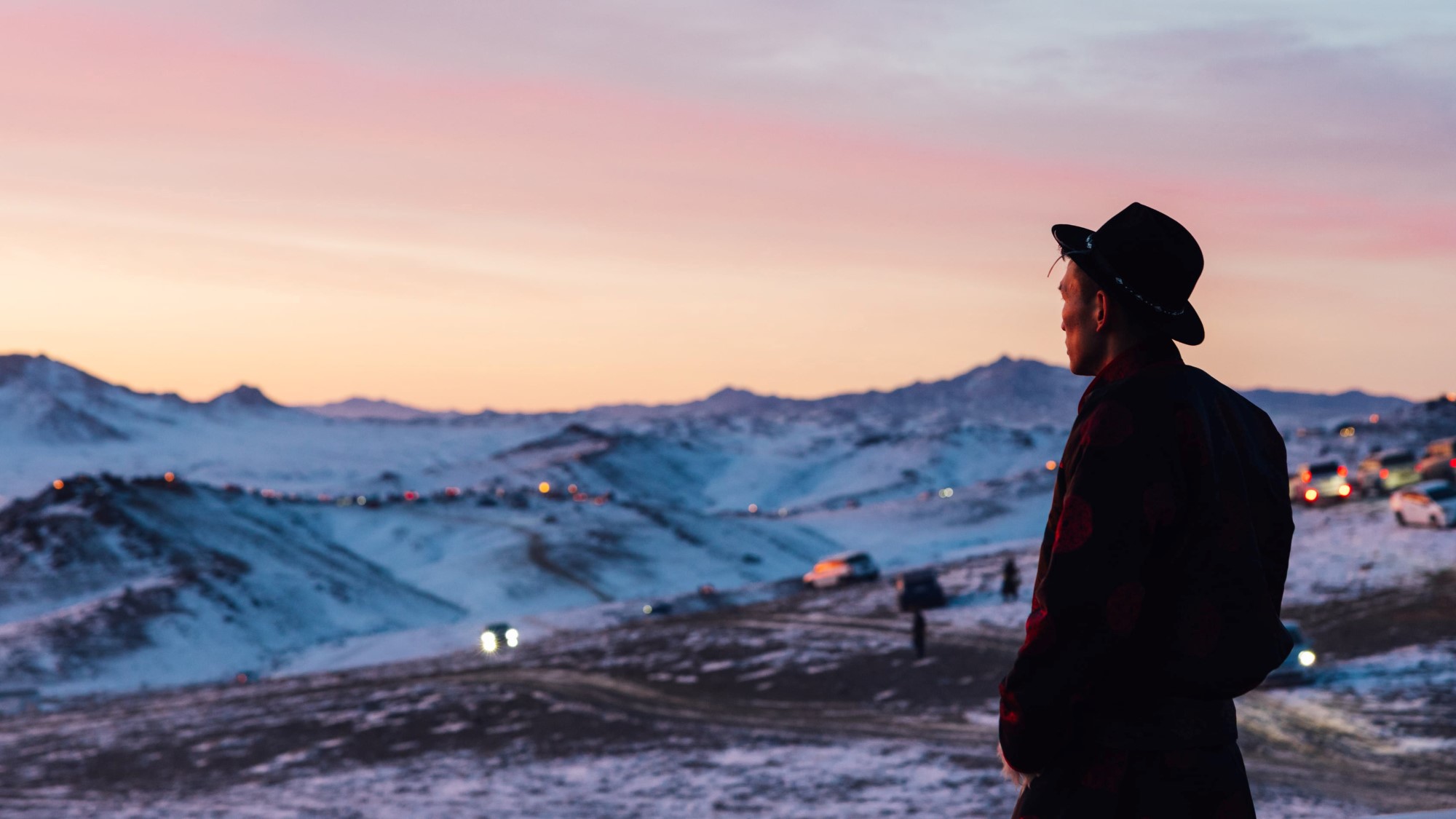 Mongolsk mann ser utover landskap i solnedgang