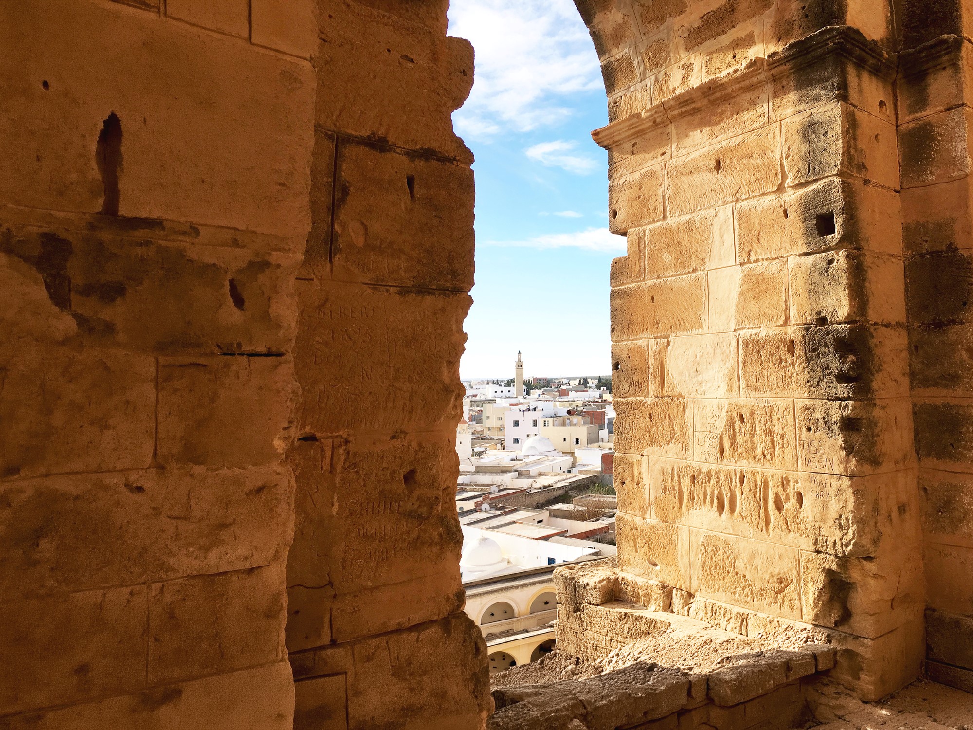 Vindusbue i gammel steinmur med utsikt over by