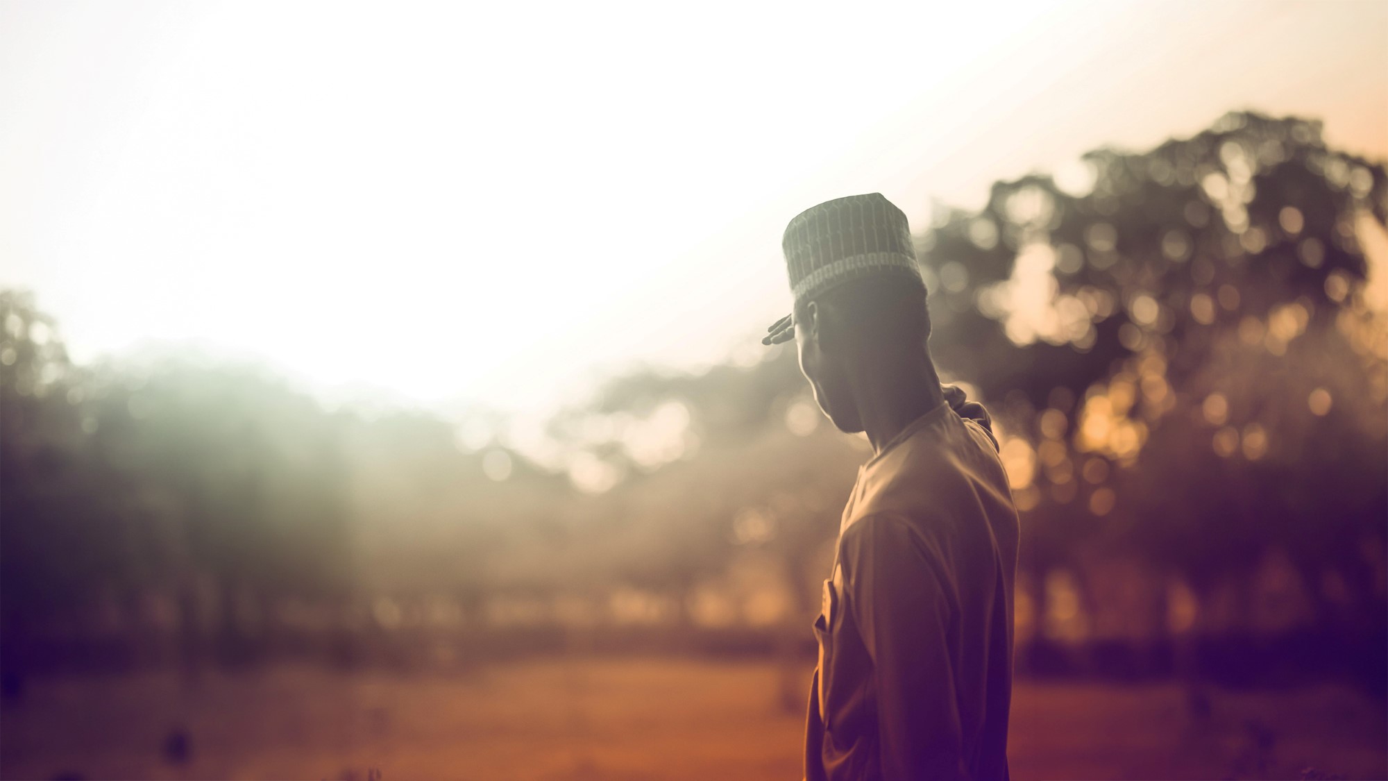 Afrikansk mann speider utover landsdkap i soloppgang