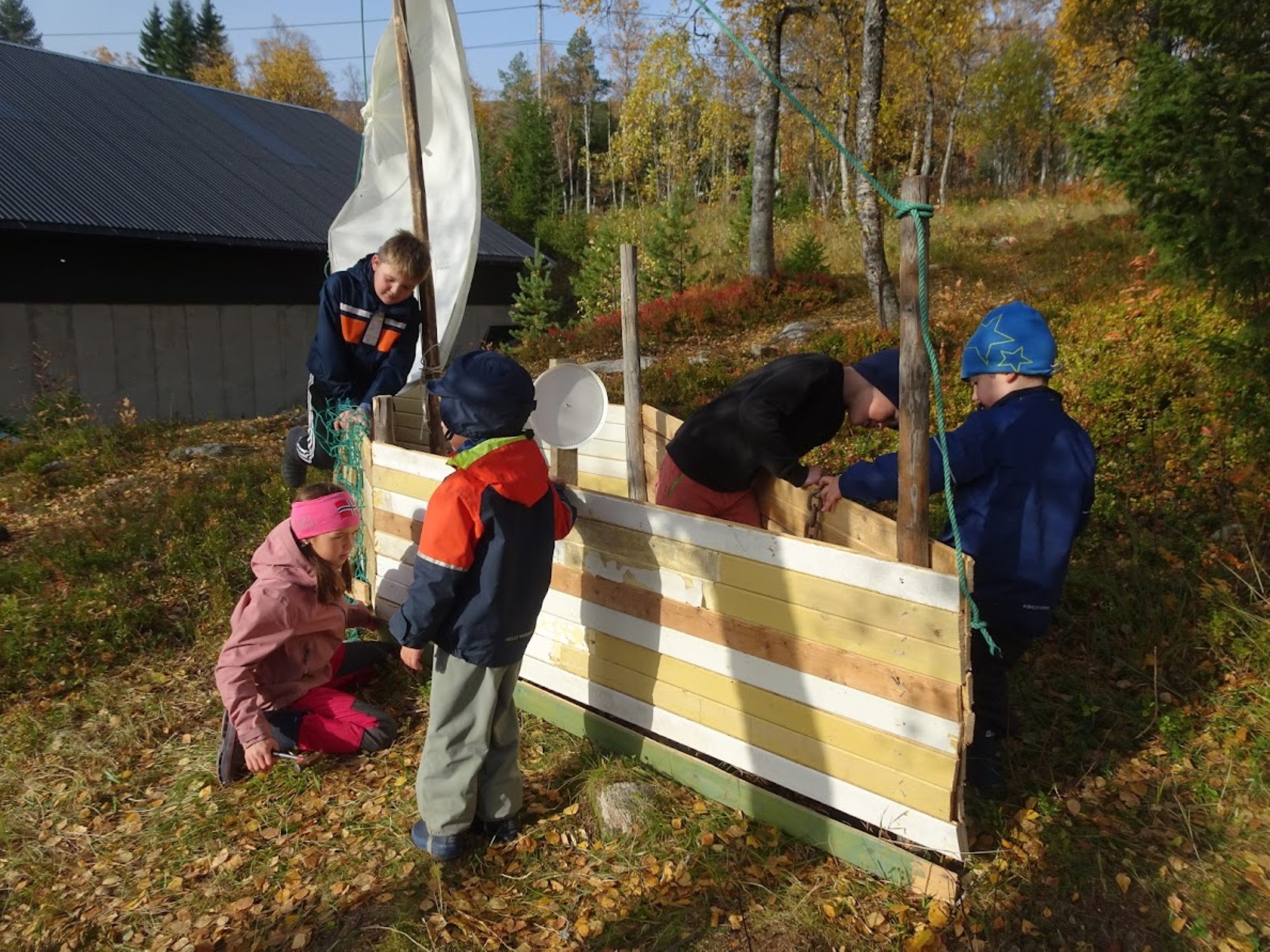 Tre barn snekrer på trebåt