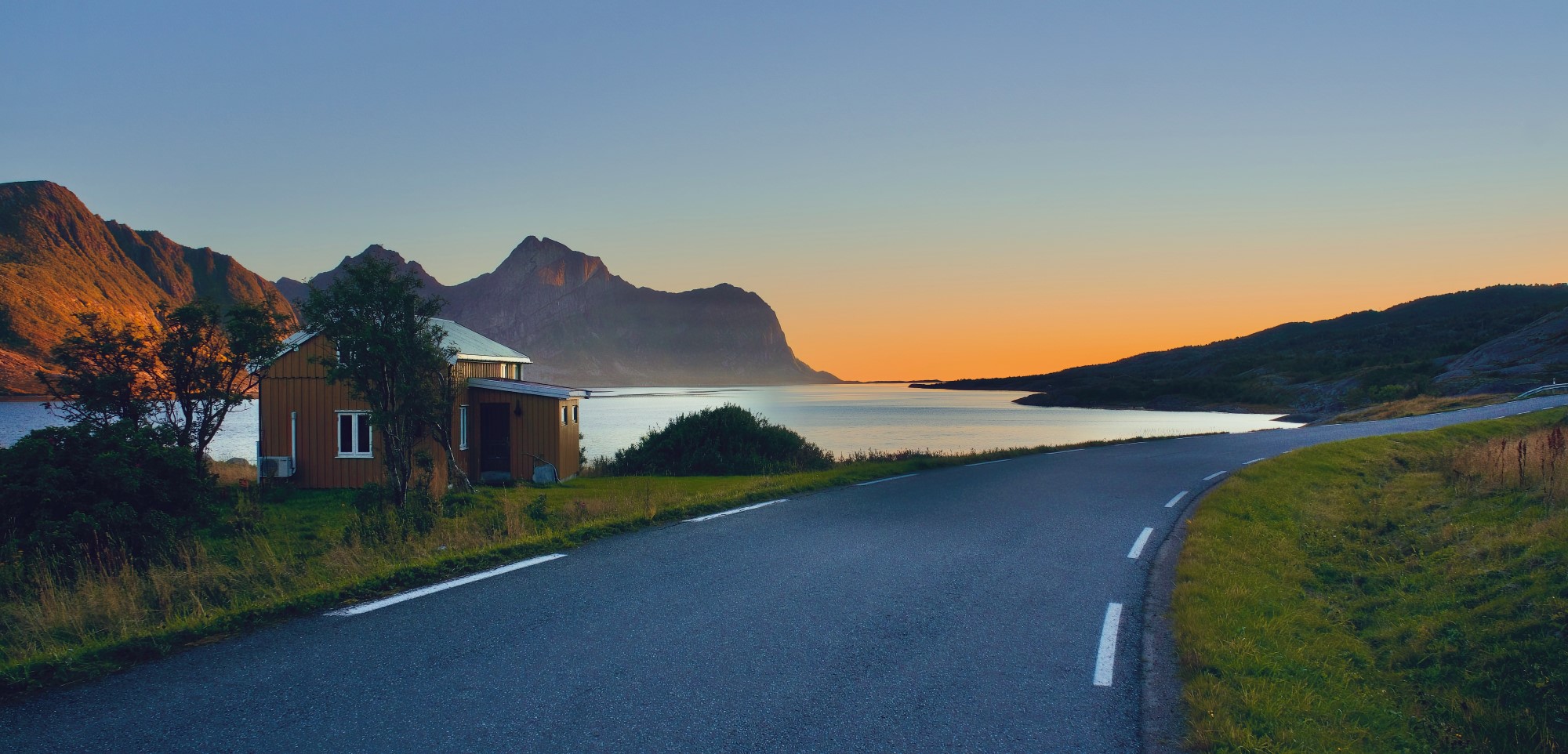 Landskap med en veil som går forbi et lite hus, lyset fra en solnedgang i horisonten