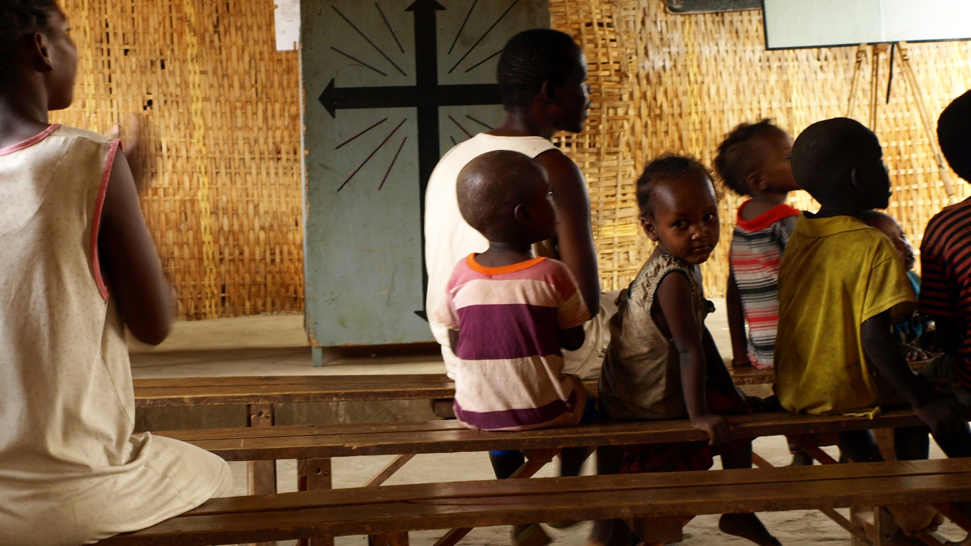 Barn på benkerad under gudstjeneste i enkel kirke
