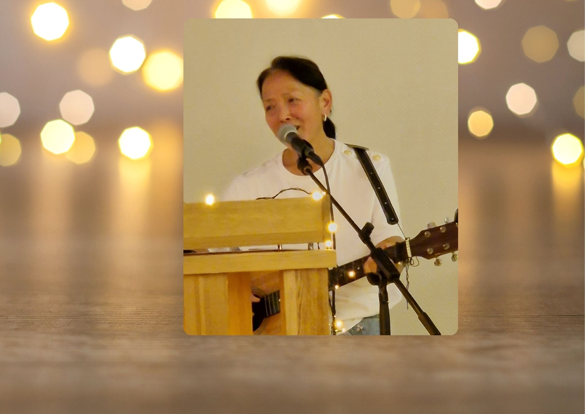 Dame med gitar, bak talerstol. Glitrende, gylden bakgrunn