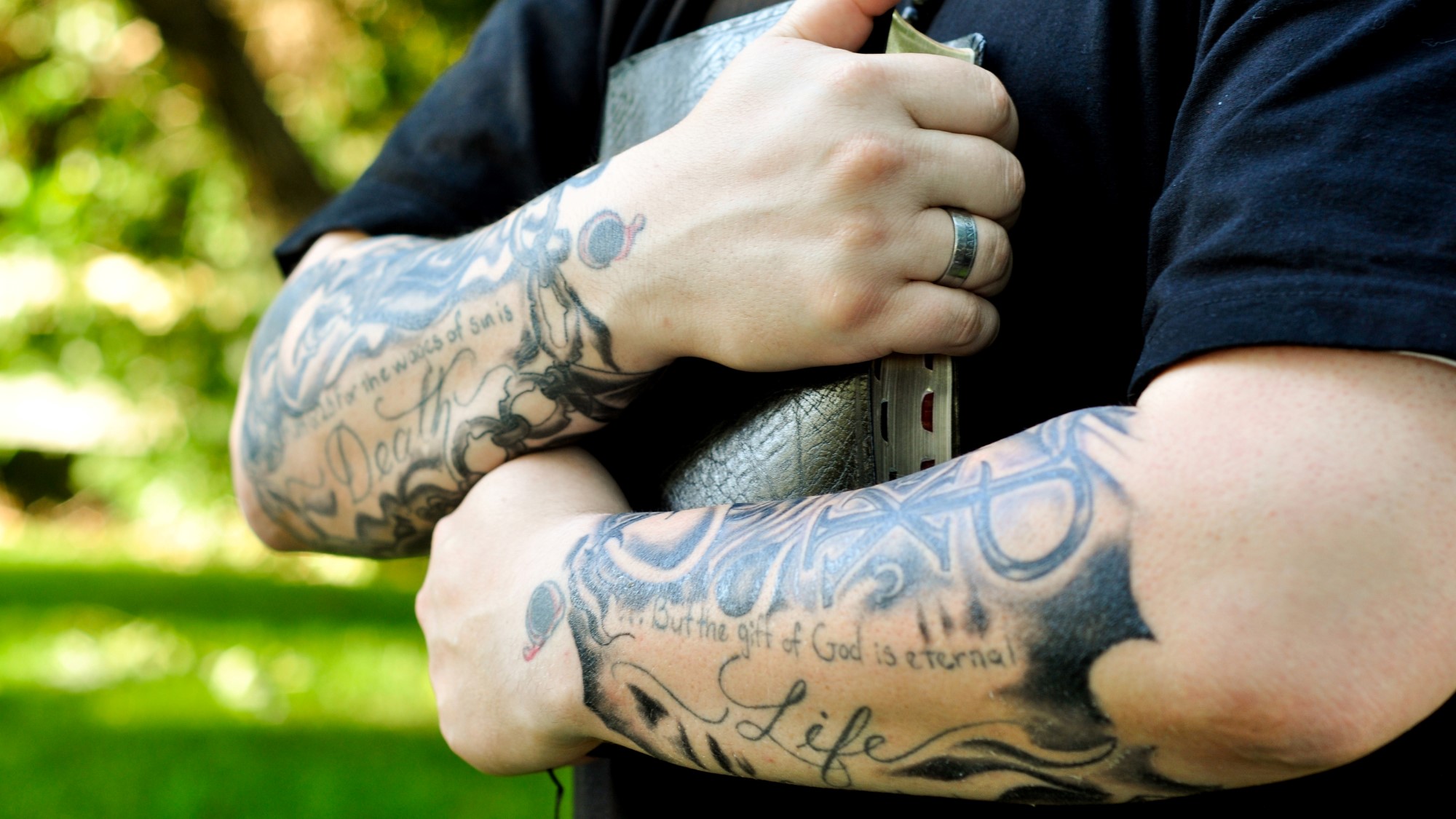 Mann med tatoveringer holder bibel tett mot brystet